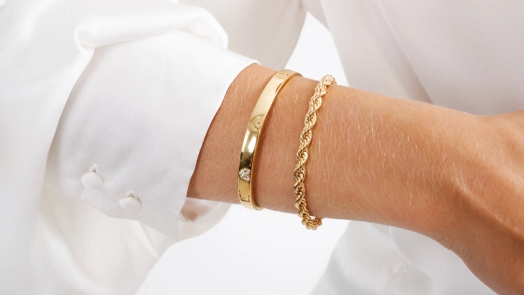 Close-up of a woman's wrist featuring Elladora's stylish gold bangle and twisted bracelet, highlighting the luxurious and durable design made in Brazil.