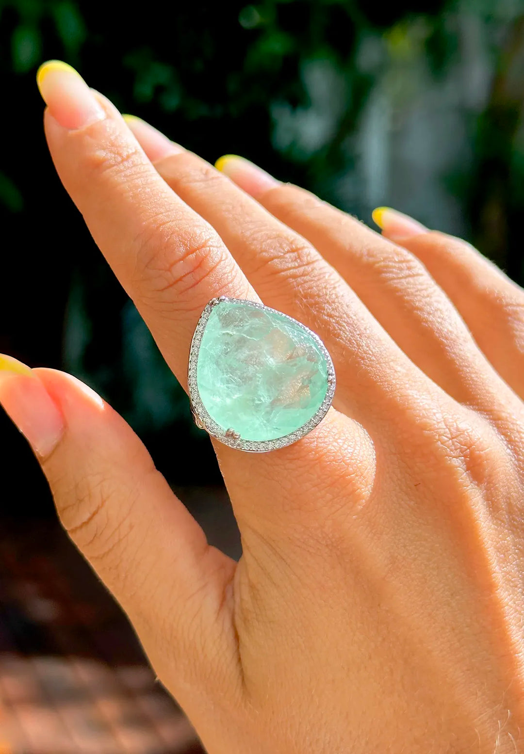 Close-up of a hand adorned with Elladora's statement fusion stone ring, with a sparkling encrusted border enhancing the gem's natural beauty.