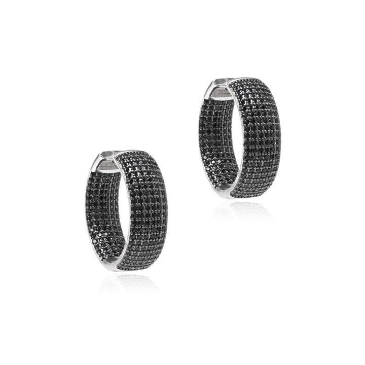 A pair of silver hoop earrings with a textured, pave-set black crystal pattern, displayed on a clean white background with a subtle reflection.