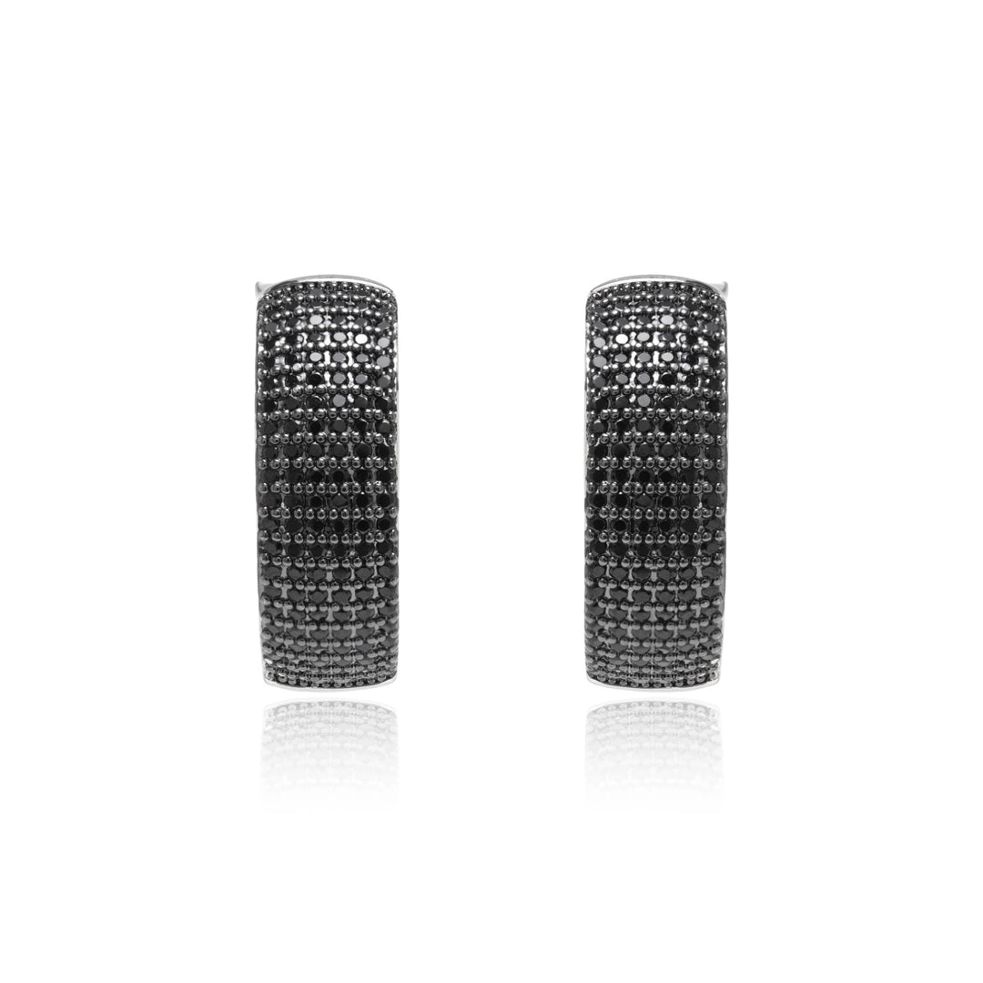 A pair of silver hoop earrings paved with small black stones, shown against a plain white background with a soft reflection below.