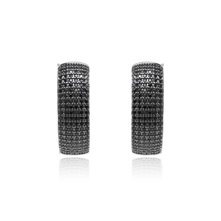 A pair of silver hoop earrings paved with small black stones, shown against a plain white background with a soft reflection below.