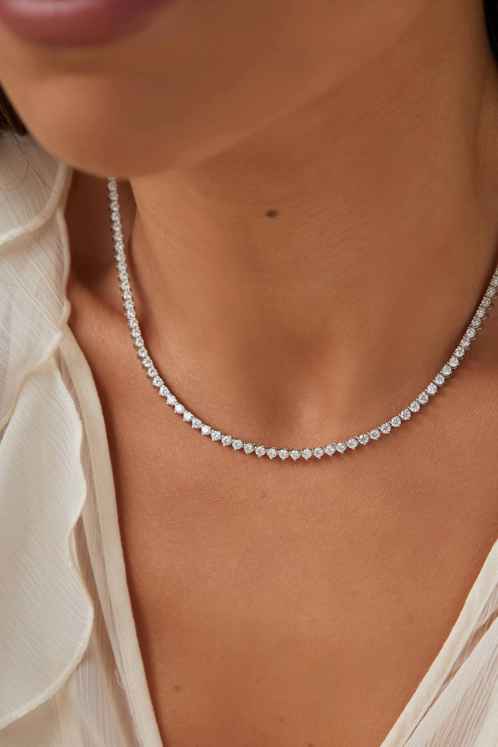 Close-up of a person wearing a delicate moissanite silver tennis necklace.