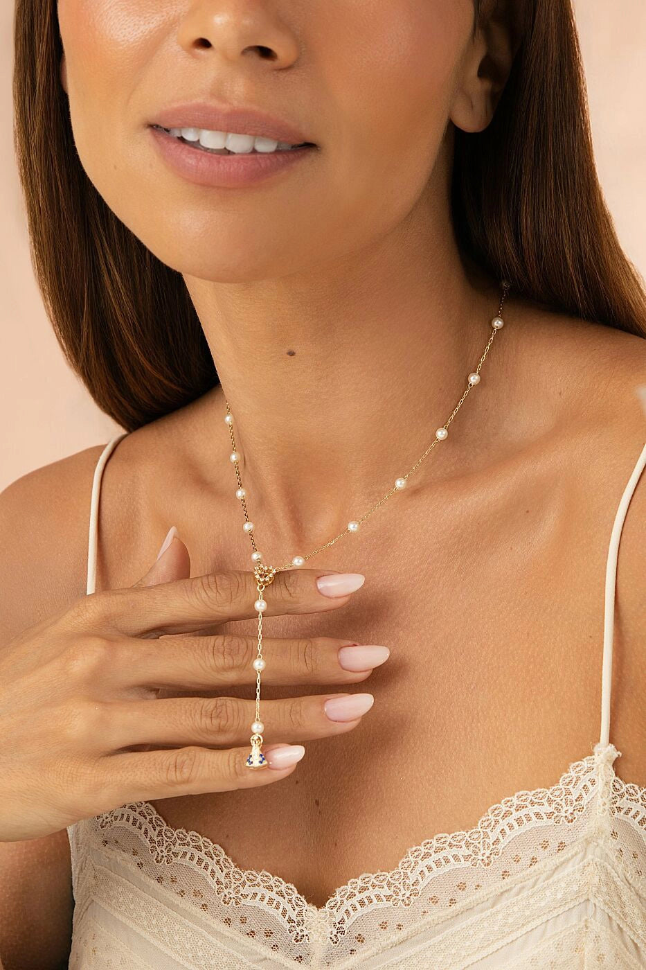 Woman wearing a delicate pearl necklace with a soft pink background