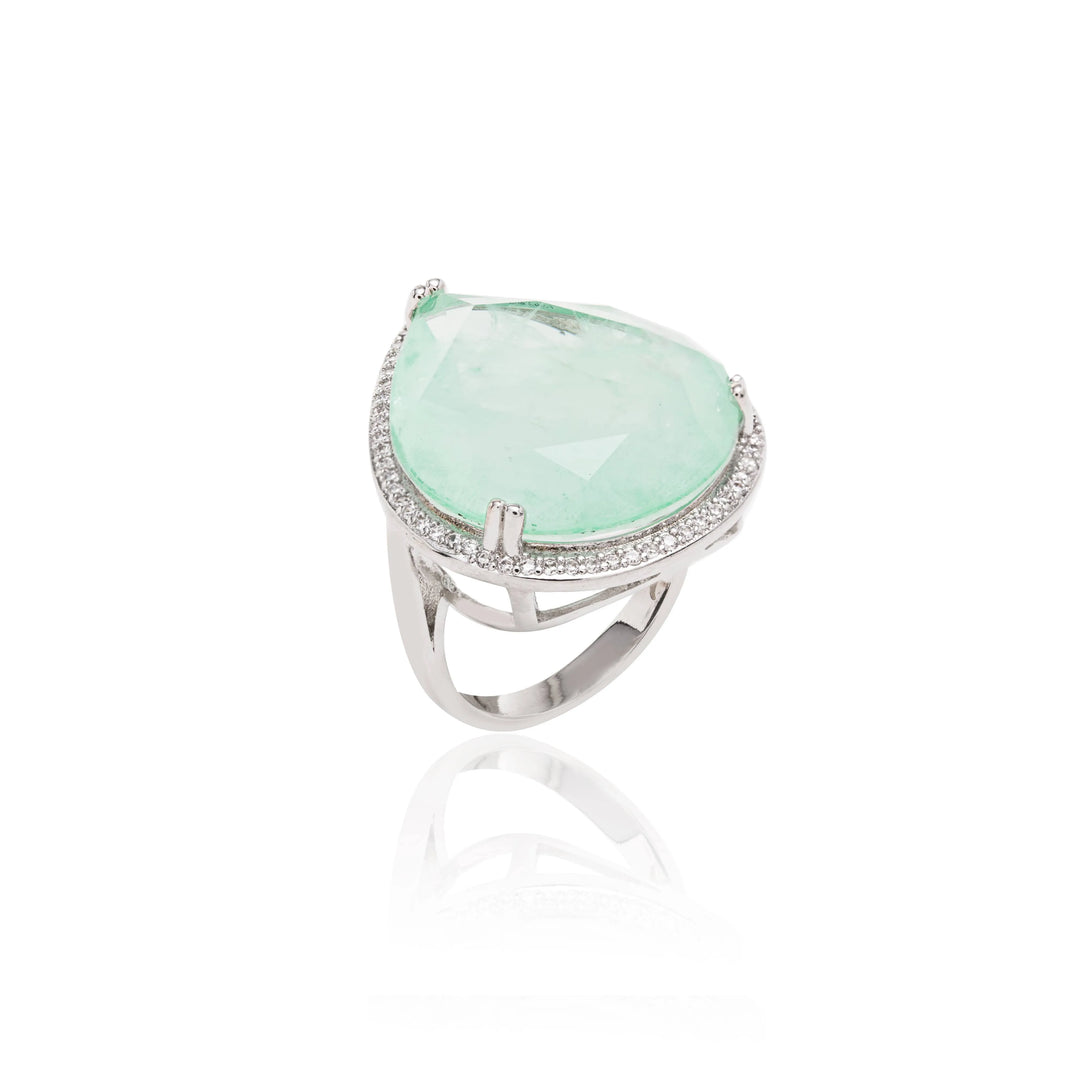 A rhodium-plated ring with a green Colombian emerald in the center and smaller clear crystals around it.