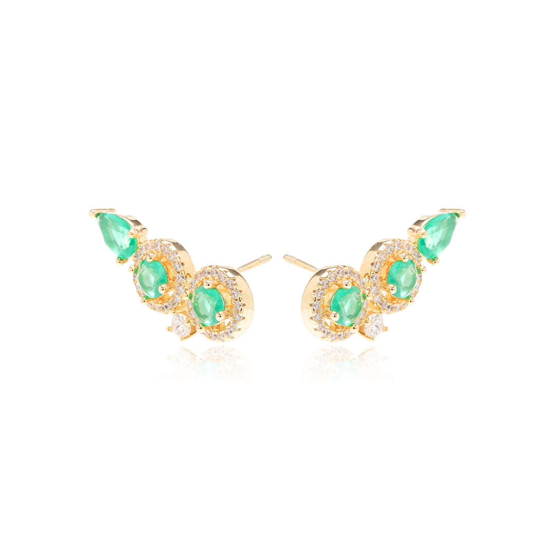 A pair of gold crescent-shaped stud earrings featuring green emerald-cut gemstones and small clear accent stones, displayed on a clean white background with a soft reflection.