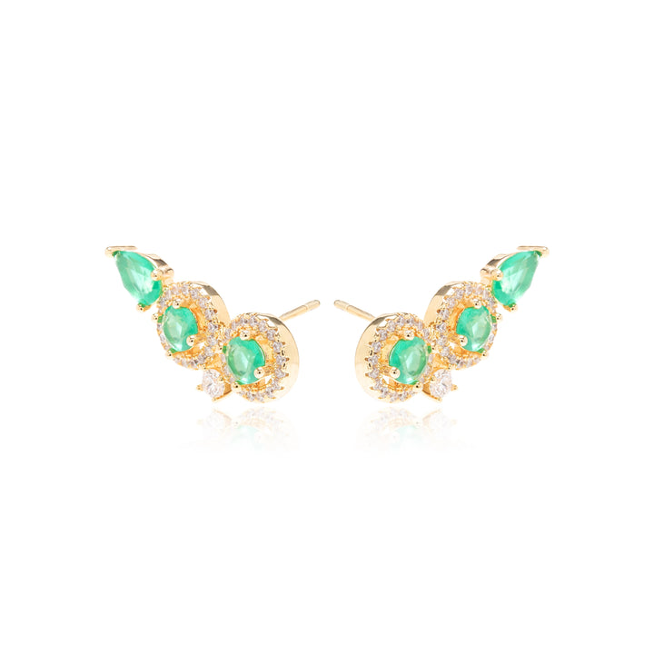 A pair of gold crescent-shaped stud earrings featuring green emerald-cut gemstones and small clear accent stones, displayed on a clean white background with a soft reflection.