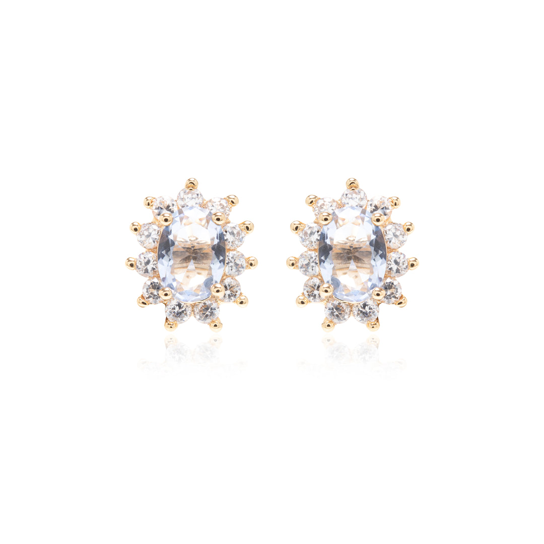 A pair of gold stud earrings featuring oval clear gemstones surrounded by small round-cut accent stones, set against a plain white background.