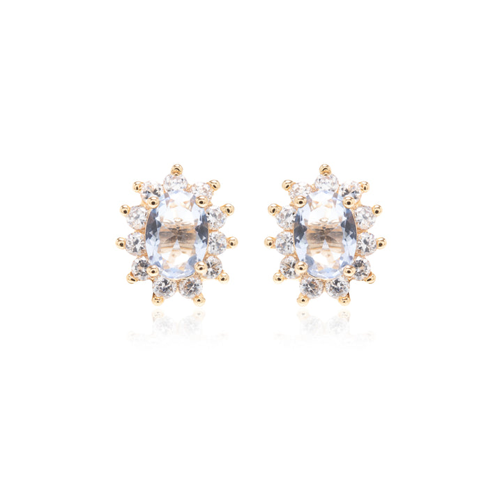 A pair of gold stud earrings featuring oval clear gemstones surrounded by small round-cut accent stones, set against a plain white background.