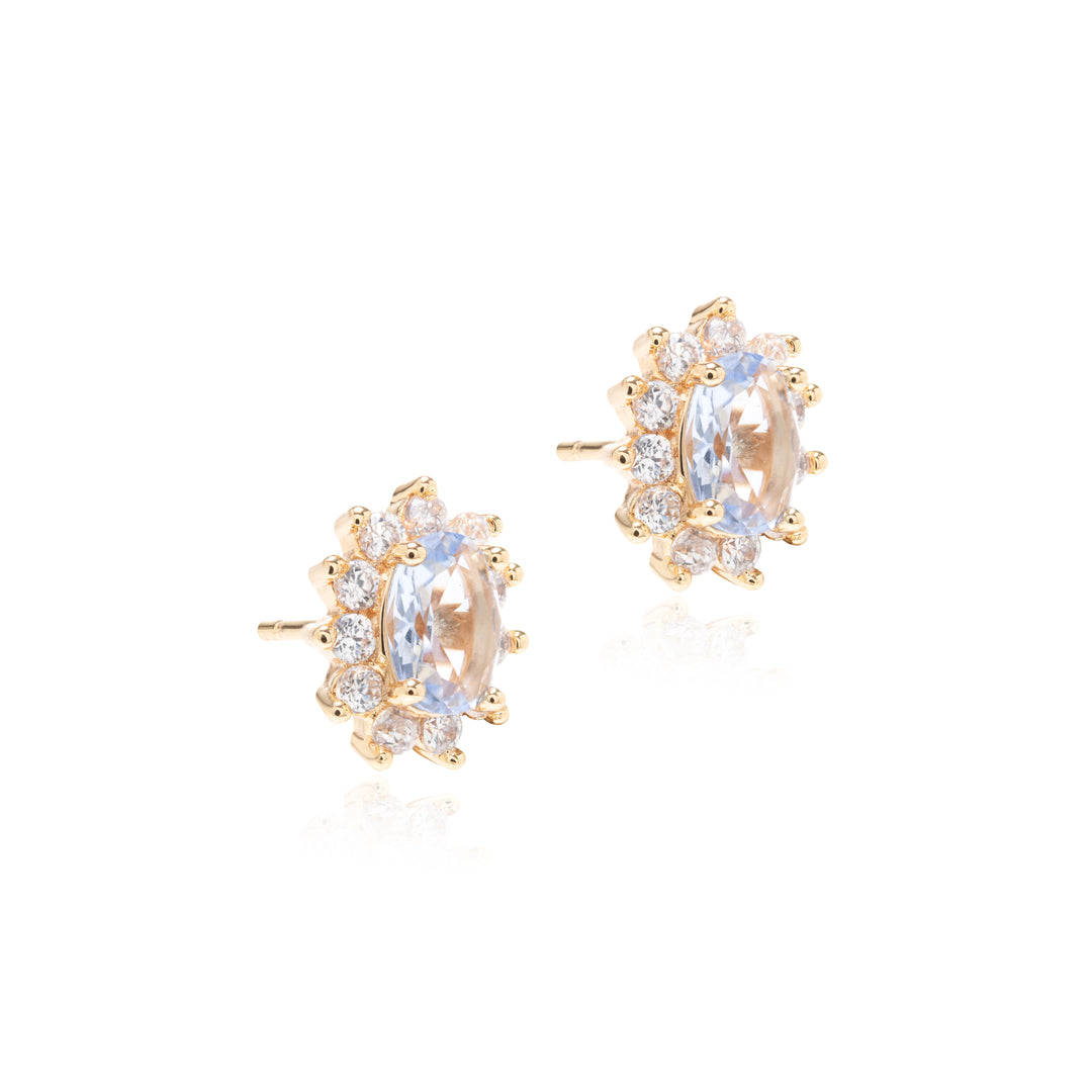A pair of gold stud earrings featuring oval clear center stones surrounded by small round clear stones, shown on a clean white background.