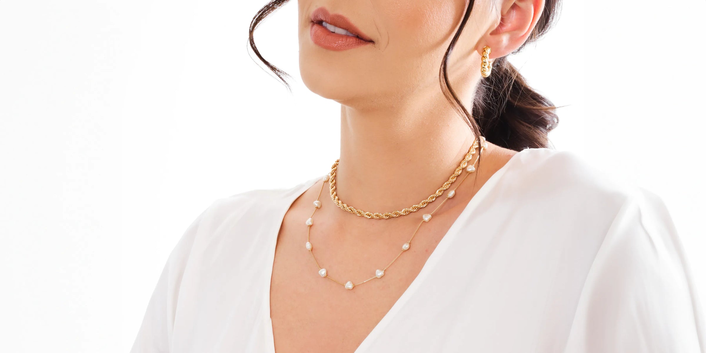 Chic gold jewellery ensemble with pearl accents presented by a stylish woman, perfect for both casual and formal attire