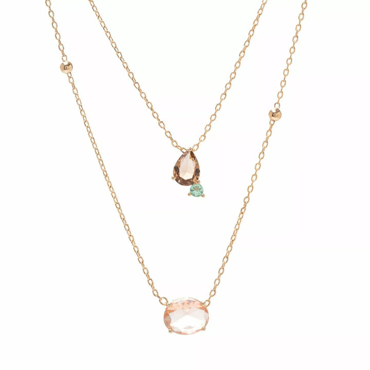 A double-layered rose gold necklace set on a white background. The shorter chain features a small pear-cut pink stone and a tiny mint green accent, while the longer chain features a larger oval pink stone pendant.