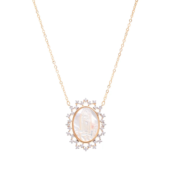 A gold necklace with an oval pendant featuring a white mother-of-pearl Virgin Mary figure, surrounded by small clear stones, on a plain white background.
